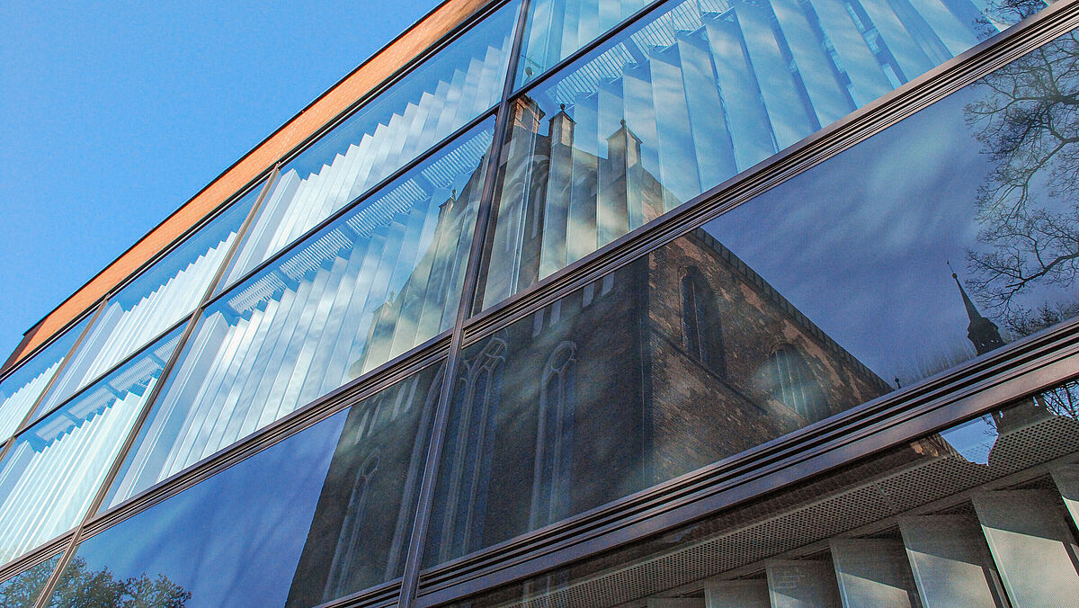 Alfried Krupp Wissenschaftskolleg; Gläsernes Fassade des Alfried Krupp Kollegs mit Spiegelung des Greifswalder Doms. 